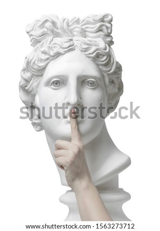 Sign of silence. Gypsum statue of Apollo's head with finger on lips. Eyes wide open. Statue. Silence. sssh. Verbosity. Quiet. Omicron. Coronavirus. Connection. Keep silence. Secret concept. Cloning