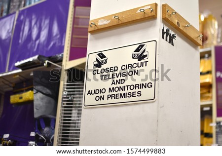A sign in a store warns shoppers that they are being monitored on a closed-circuit television cctv camera.