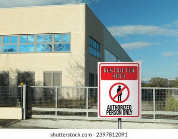 Sign with text Restricted Area Authorized Person Only on fence near factory building outdoors - Powered by Shutterstock