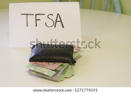 a sign that says TFSA next to a wallet that has money in it. Theme of Canadian savings. TFSA stands for tax free savings account