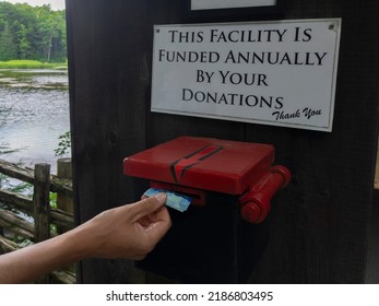 Sign This Facility Is Funded Annually By Your Donations Thank You, Man Is Putting 5 Dollar Bill In The Donation Box. Selective Focus. Charity, Generosity, Not For Profit And Volunteering Concept.