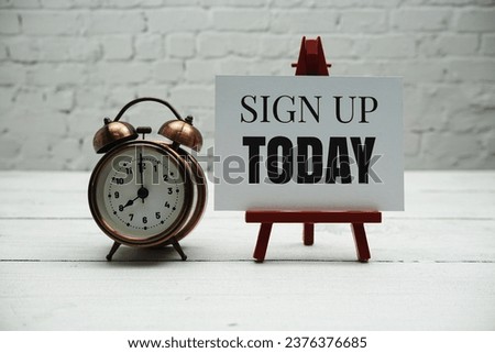 Sign up Today text and alarm clock on white brick wall and wooden background