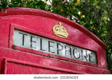 Sign at the top of a classic red British telephone box, featuring a gold crown - Shutterstock ID 2312056325
