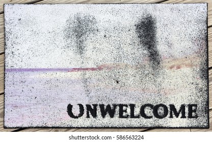 A Sign For Unwelcome Visitors. Dirty, Worn, And Faded UNWELCOME Mat.