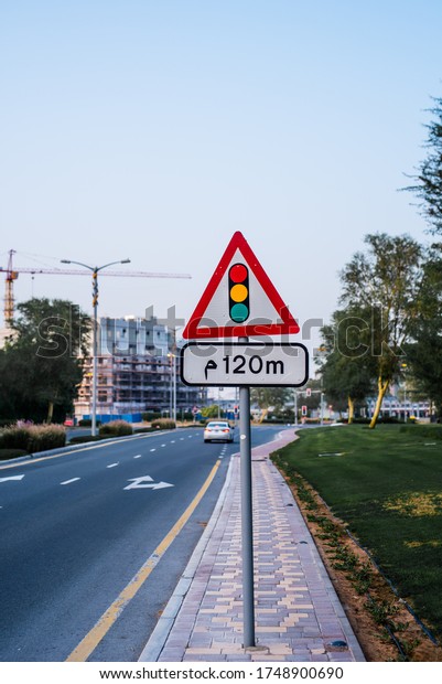 Signal after 120 meters. Traffic light sign\
with road and trees on the background.\
