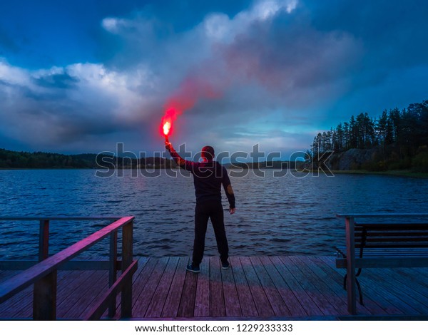 Signal for help. A man signals a torch\
in his hand. SOS. A man holds a torch in his\
hand.