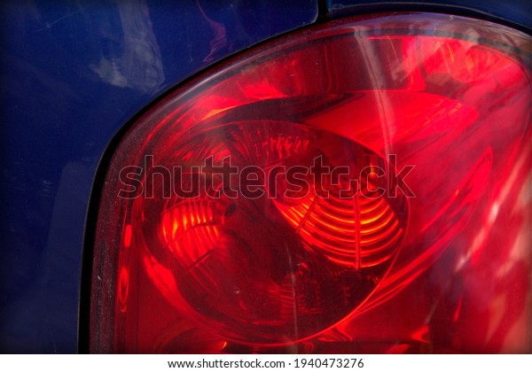 Signal light on the back of the car. Red headlight\
on a blue car.