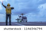 Signal man give a signal to anti-submarine warfare helicopter on the aviation deck of aircraft carrier.
