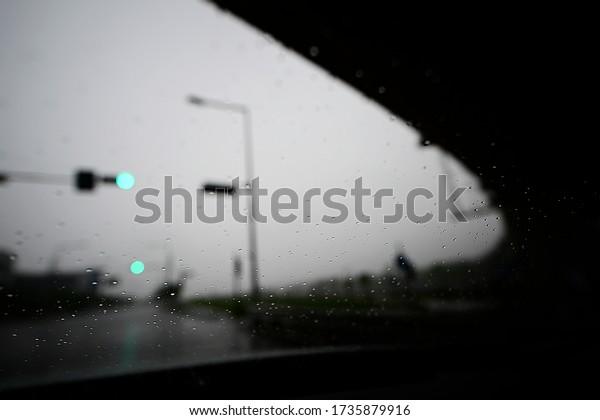 A signal seen\
as a car window on a rainy\
day.