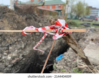 Signal Tape Serves As Warning Measures To Avoid People Falling In The Dug Trench. Red And White Warning Tape Waving On Wind Is Extra Safety Measures