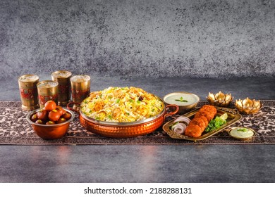 Signature Classic Combo Indian Food Butter Chicken Biryani Or Murgh Makhani Biryani With Raita, Shami Kabab, Drinks And Gulab Jamun Served In A Dish Side View Ramadan Family Deal On Grey Background