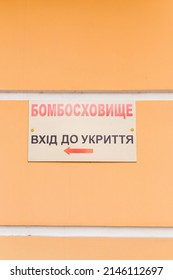 Signboard with inscription in Ukrainian - Bomb Shelter. Refuge entrance - on orange wall. War in Ukraine 2022. Russian invasion. Vertical shot