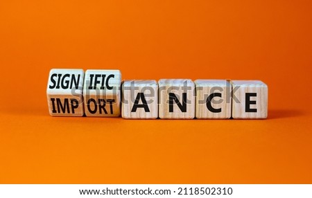 Significance and importance symbol. Turned wooden cubes and changed the word importance to significance. Beautiful orange background, copy space. Business, significance and importance concept.