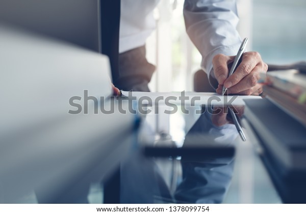 Signing contract, business deal concept. Businessman,\
executive manager working in modern office, make a deal, signing\
business contract with laptop computer, digital tablet on office\
desk. 