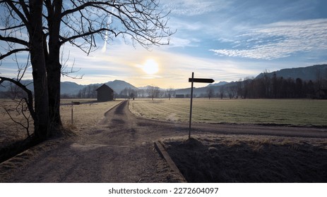 Signpost on country road next to tree with wooden hut and mountains in background in winter morning at sunrise - Powered by Shutterstock