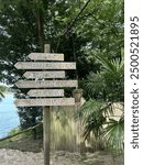 signpost, orientation byron bay, sunshine coast, boomerang beach australia, beach bar, music, wakeboard, trees and beach in the back, sandy floor and bamboo fence