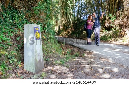 Signpost of Saint James way with pilgrims pointing the path in the background
