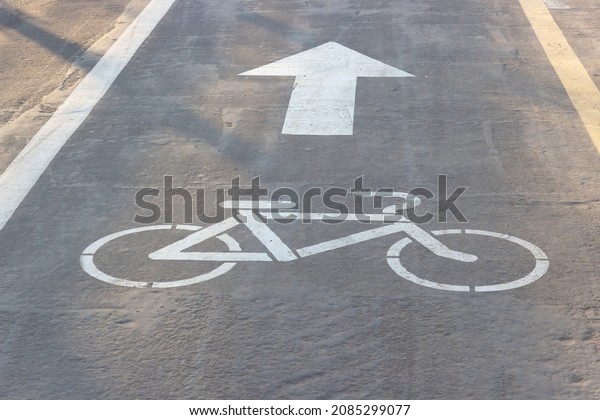 Signs of Bike and Arrow on the asphalt. Sidewalk\
for cyclists. White road markings on pavement. Bike lane symbol.\
Indicates the direction of\
movement