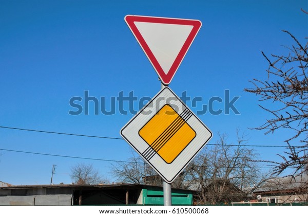 Signs give way and the end of the main road on\
blue sky background
