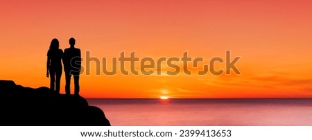 Sihouette of a man and a woman on a cliff at sunset 