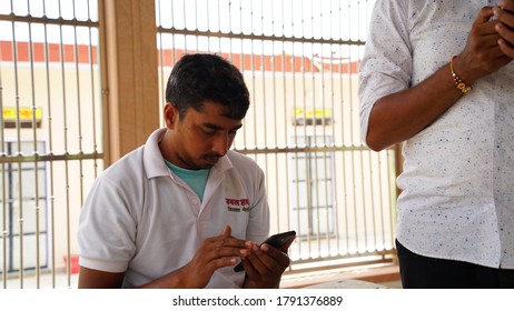 Sikar, Rajasthan, India - Aug 2020:  Handsome Indian Man Wearing Casual White T-shirt Sitting And Checking His WhatsApp Status