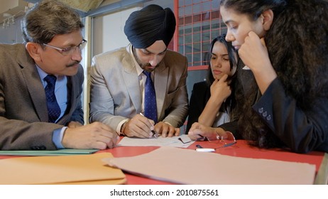 A Sikh Man Wearing The Black Turban With His Colleagues From India In The Workplace Having A Meeting