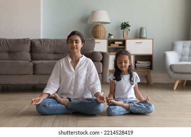 Silent Indian woman and preschooler 5s serene daughter meditating seated in lotus position on warm floor in modern living room. Good life habit, healthy lifestyle, yoga practice with children at home - Shutterstock ID 2214528419