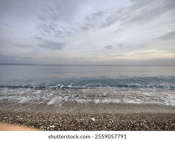 The Silent Shore: A Metaphor of Endless Horizons and Fleeting Waves, Where Pebbled Stillness Meets the Moody Sky, Reflecting a Timeless Serenity Amid the Calm Before the Storm in Nature’s Unspoken. - Powered by Shutterstock