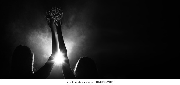 Silhouette abstract of two hands try to reach Diamond Crown as Miss Beauty Queen Pageant Contest as final competition, finale winner moment. very low exposure dark background copy space - Shutterstock ID 1848286384