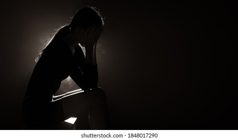 Silhouette abstract of woman expresses feeling sad, cry and loneliness from broken heart and problem. Backlit smoke low exposure dark background copy space