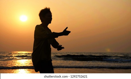 Silhouette of active senior woman practicing tai chi gymnastic on sandy beach at sunset. - Powered by Shutterstock