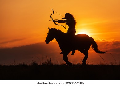 Silhouette against the setting sun, woman riding in historical costume as a warrior