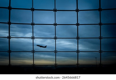 Silhouette of an airplane against a window with square grids and a stormy sky in the background