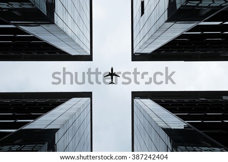 Silhouette of an airplane flying into the crosshair of a symmetrical highrise building.
