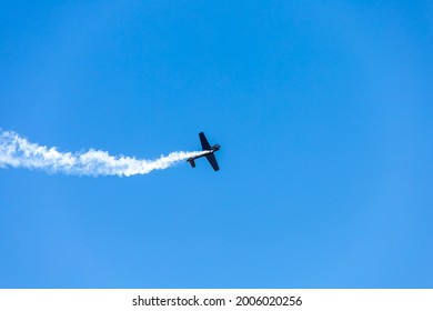 Silhouette Airplane Stunt Fly Over Clear Blue Sky. Aerobatic Glide With Engine Smoke Behind, Power Speed Transportation. Aviation Concept With Copy Space