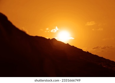 silhouette of alone man standing on horizon line, top of mountain and looking at sunset cloudy sky. back, rear view. Young male standing on high rock at sunrise and enjoying view of evening nature