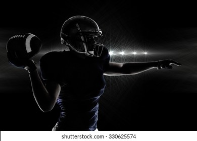 Silhouette American football player throwing ball against spotlights - Powered by Shutterstock