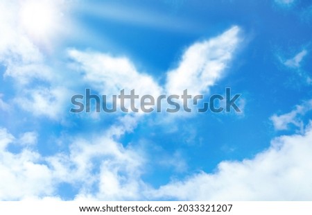 Silhouette of angel's wings made of clouds in blue sky 