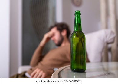 Silhouette Of Anonymous Alcoholic Person Drinking Behind Bottle Of Alcohol. Man Fighting With Alcoholic Habits, Drink Sitting On Sofa At Home