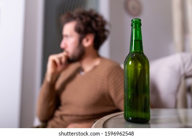 Silhouette Of Anonymous Alcoholic Person Drinking Behind Bottle Of Alcohol. Man Fighting With Alcoholic Habits, Drink Sitting On Sofa At Home