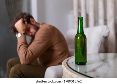 Silhouette Of Anonymous Alcoholic Person Drinking Behind Bottle Of Alcohol. Man Fighting With Alcoholic Habits, Drink Sitting On Sofa At Home