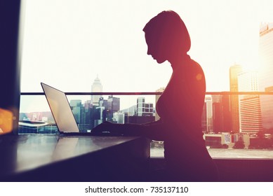 Silhouette of anonymous person using laptop comer and social networks