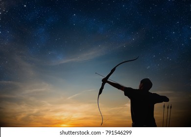 A silhouette of an archer drawing his bow and aiming upwards with colorful dramatic sky filled with sparkling stars as background
