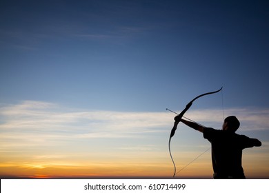 A silhouette of an archer firing an arrow towards a colorful morning sky with beautiful gradient