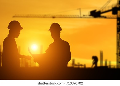 Silhouette of architect explaining the construction worker to the building plan for the correct understanding