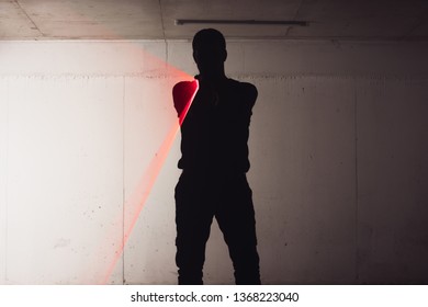 Silhouette Of An Armed Man Holding His Gun And Pointing With His Laser Beam At A Target.