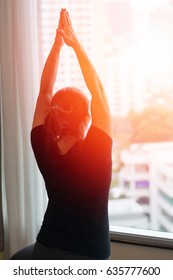 Silhouette Asia woman female worker exercise yoga in tree pose near big window, city view background with light effect.People healthcare lifestyle concept.Physical Fitness and Sports Month - Shutterstock ID 635777600