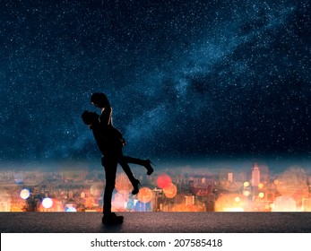 Silhouette of Asian couple, man hold his girlfriend up above the city in night under stars.