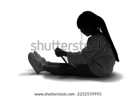 Silhouette of Asian little girl using a tablet PC.