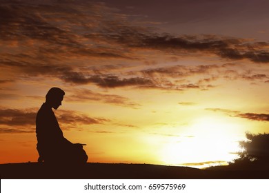 Silhouette Of Asian Muslim Man Praying On A Hilltop At Sunset